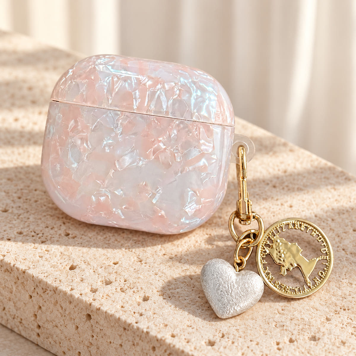 Opal Marble AirPods Case in Opal, diagonal with original attached charms on a warm cream background
