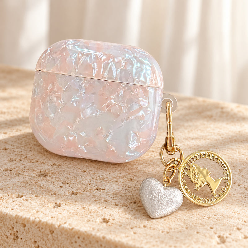 Opal Marble AirPods Case in Opal, hero with original attached charms on a warm cream background