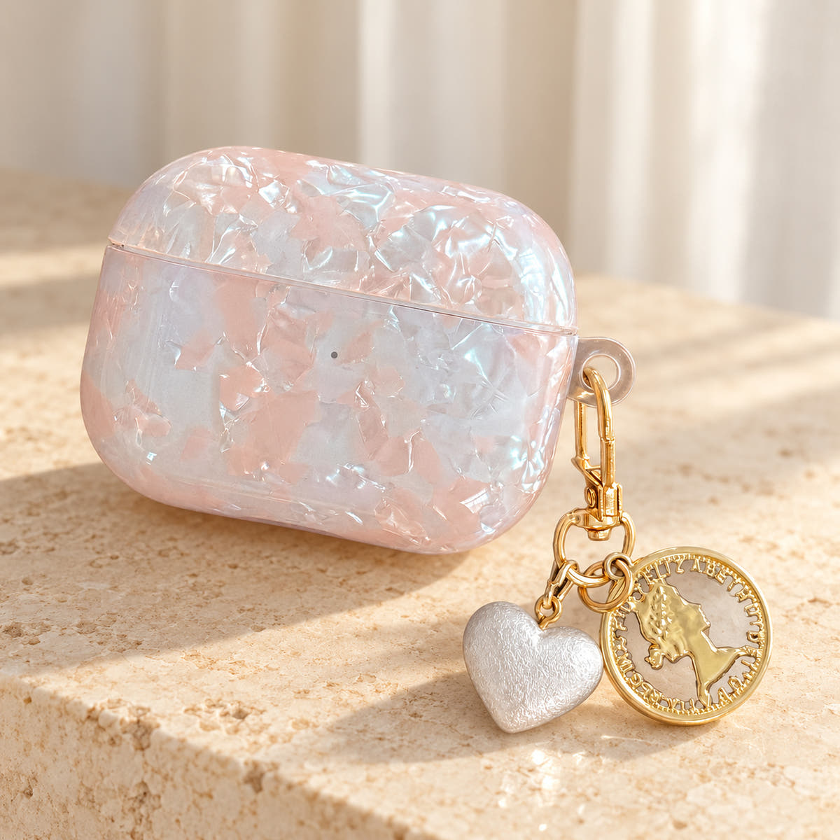 Opal Marble AirPods Case in Opal, warm light with original attached charms on a warm cream background