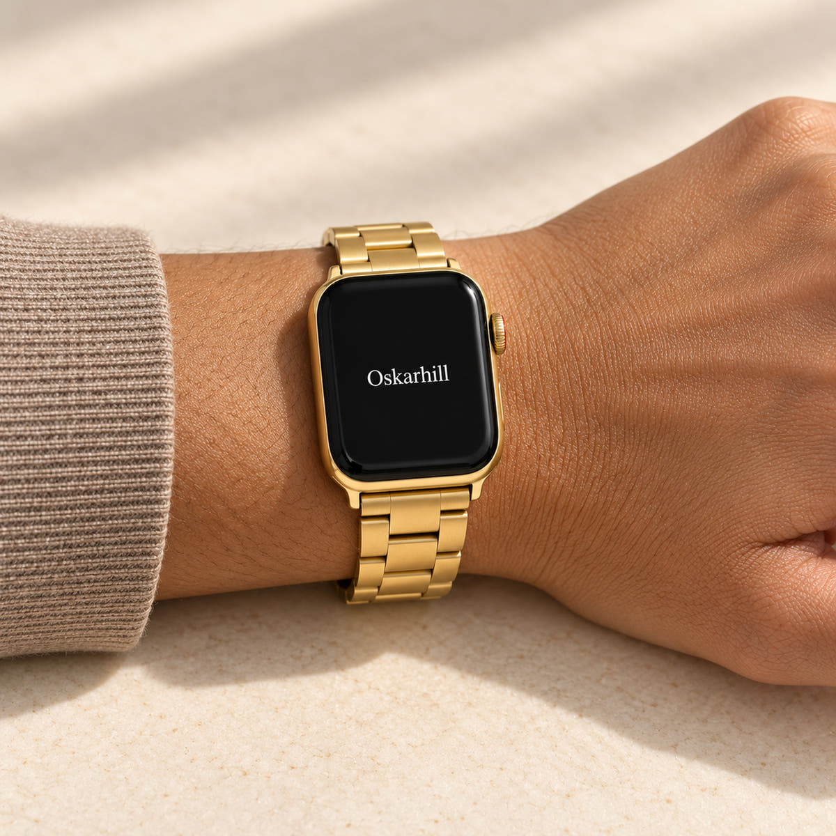 Oskar Hill Florence Gold Flat Link Apple Watch Band — close wrist view with a taupe knit sleeve