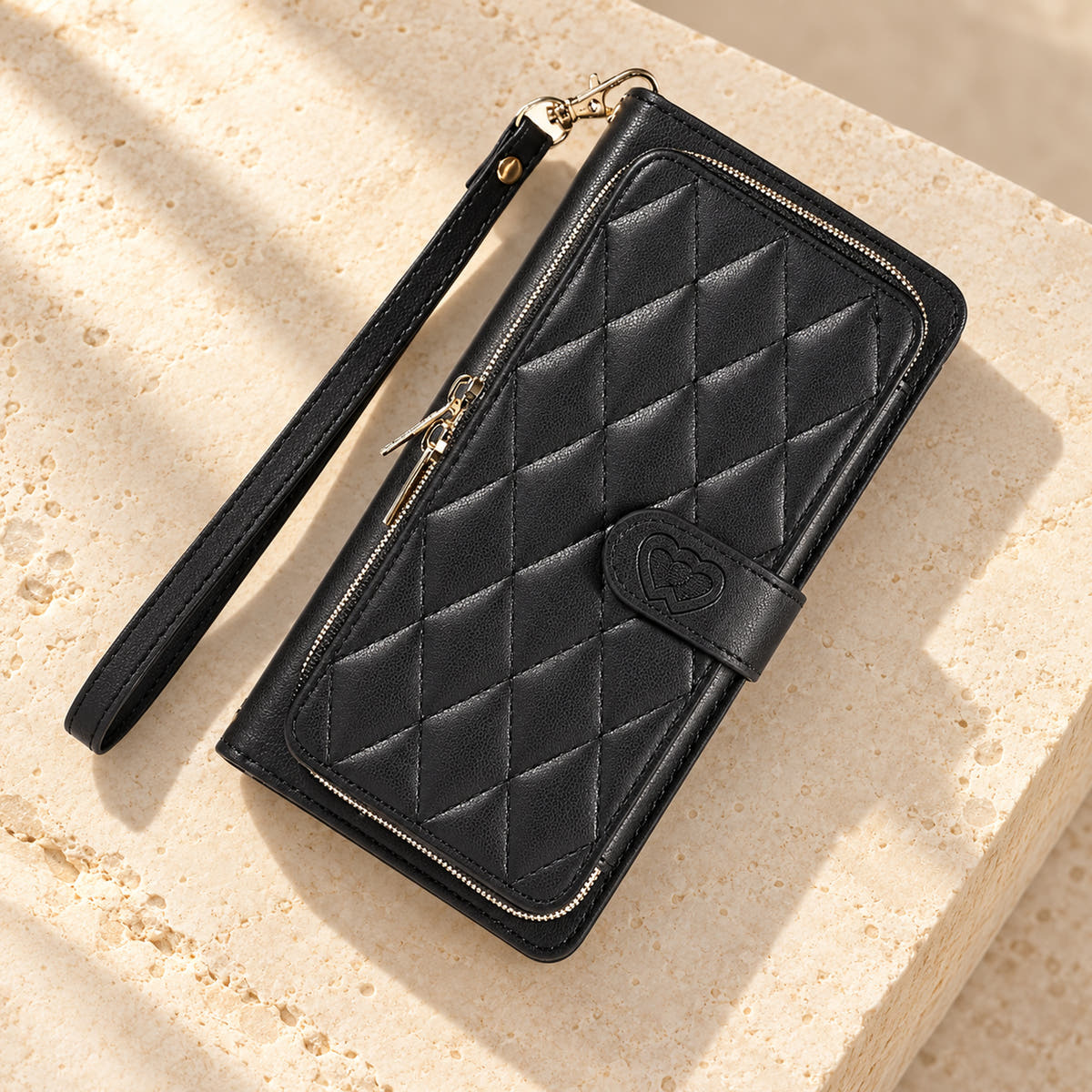 Black padded zip wallet in an angled flat lay showing quilted front and closure