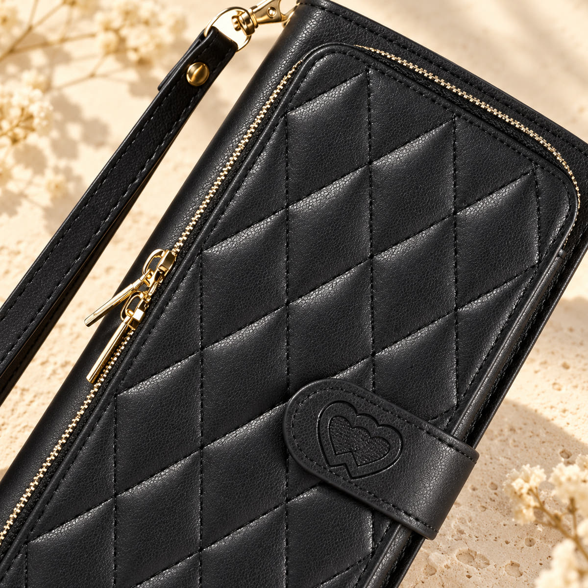 Black padded zip wallet close-up of quilting zipper and embossed heart closure