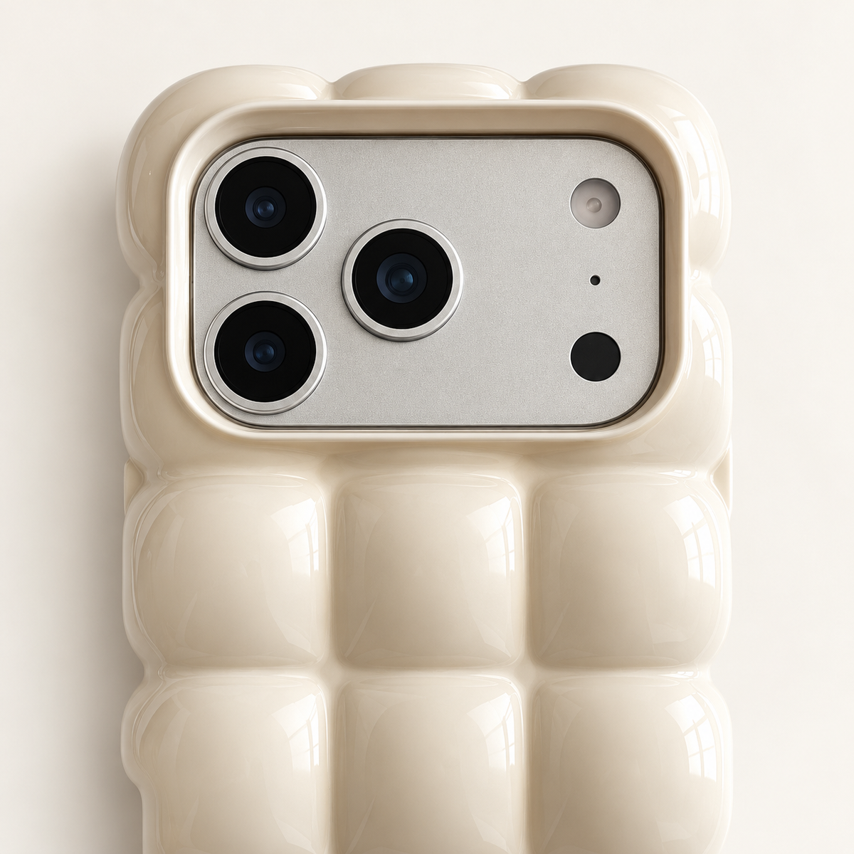 Cream puffy grid iPhone case with rounded-square back and scalloped edges — close-up of camera surround and sculpted grid.