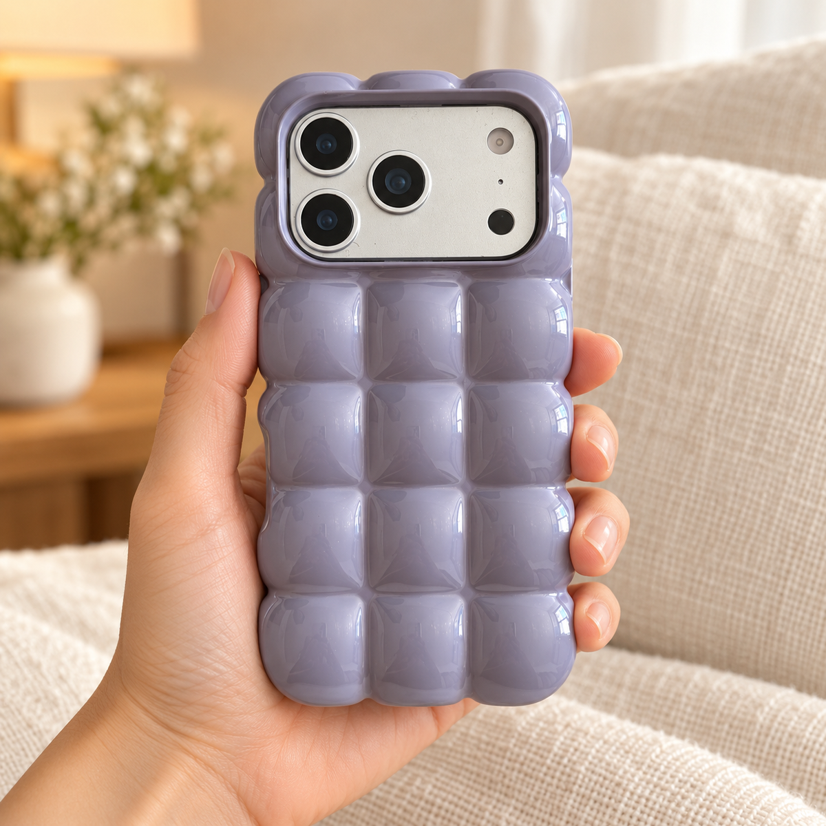 Lavender puffy grid iPhone case with rounded-square back and scalloped edges — held upright in one hand.