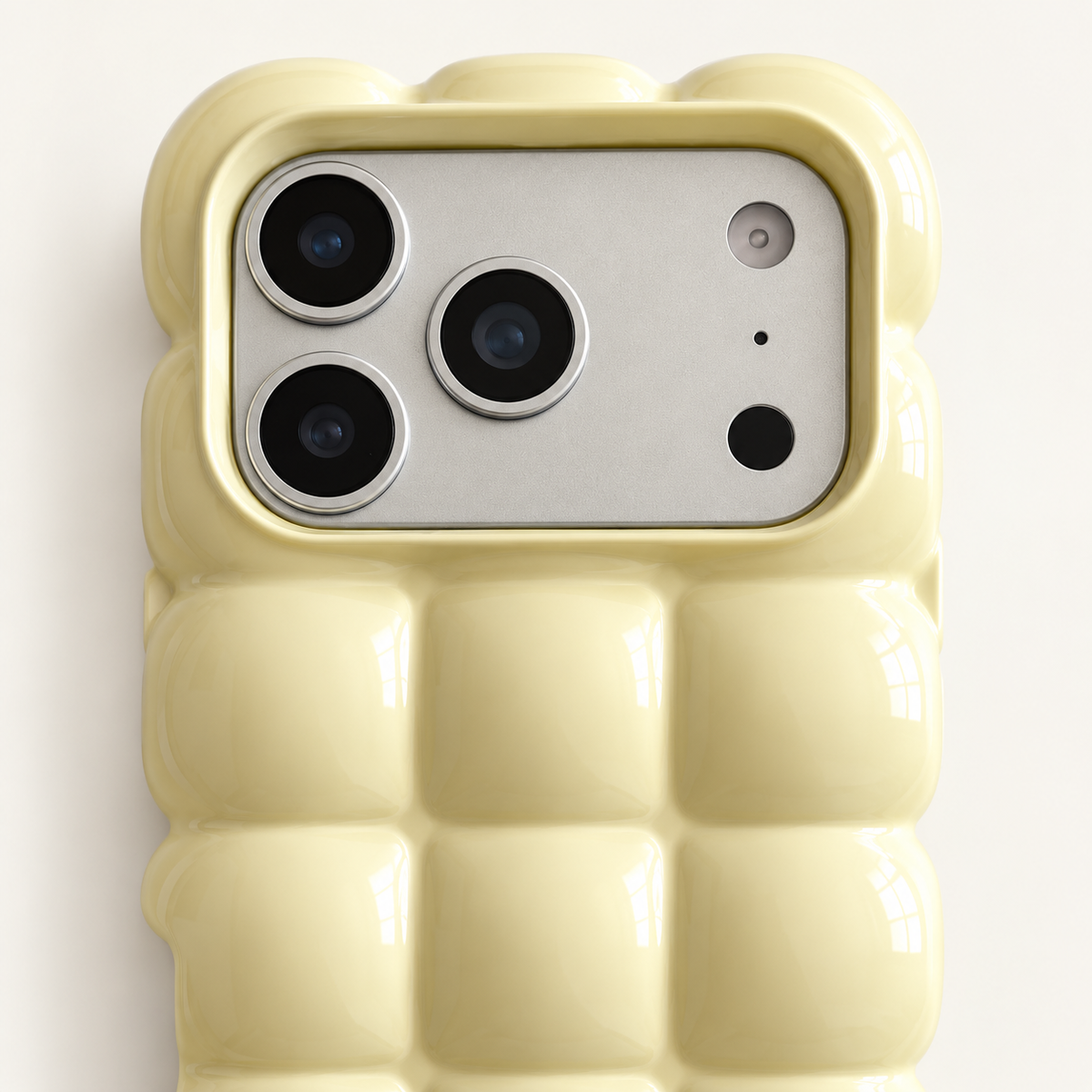 Pale Yellow puffy grid iPhone case with rounded-square back and scalloped edges — close-up of camera surround and sculpted grid.