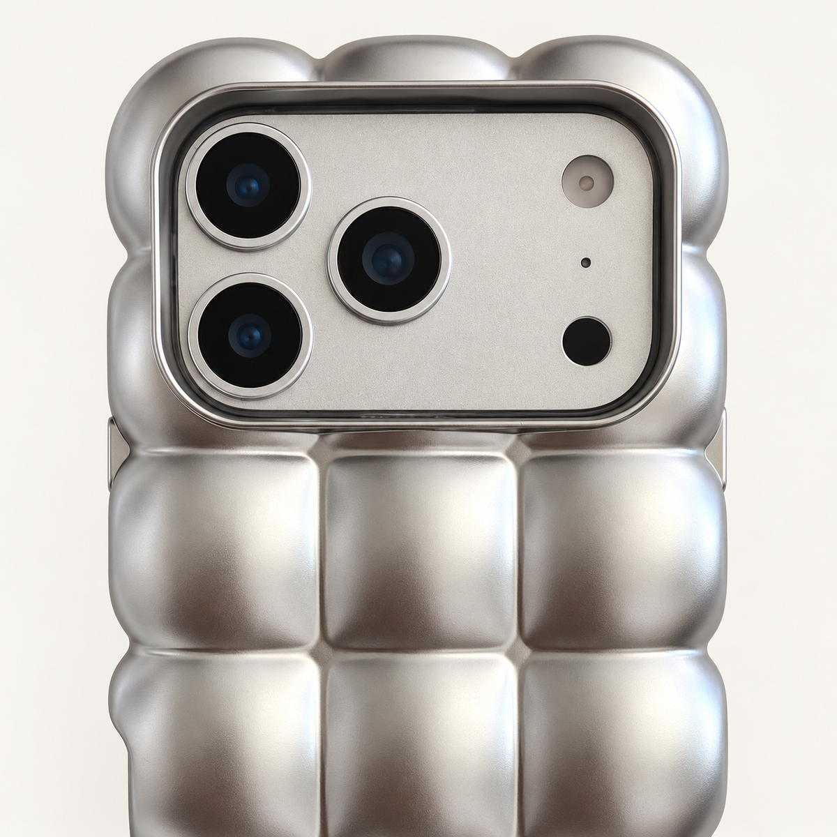 Satin Silver puffy grid iPhone case with rounded-square back and scalloped edges — close-up of camera surround and sculpted grid.