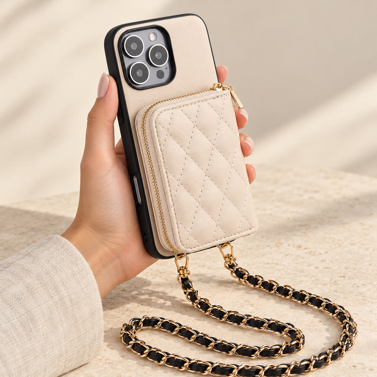 Beige quilted iPhone wallet case — handheld view with zip wallet and chain