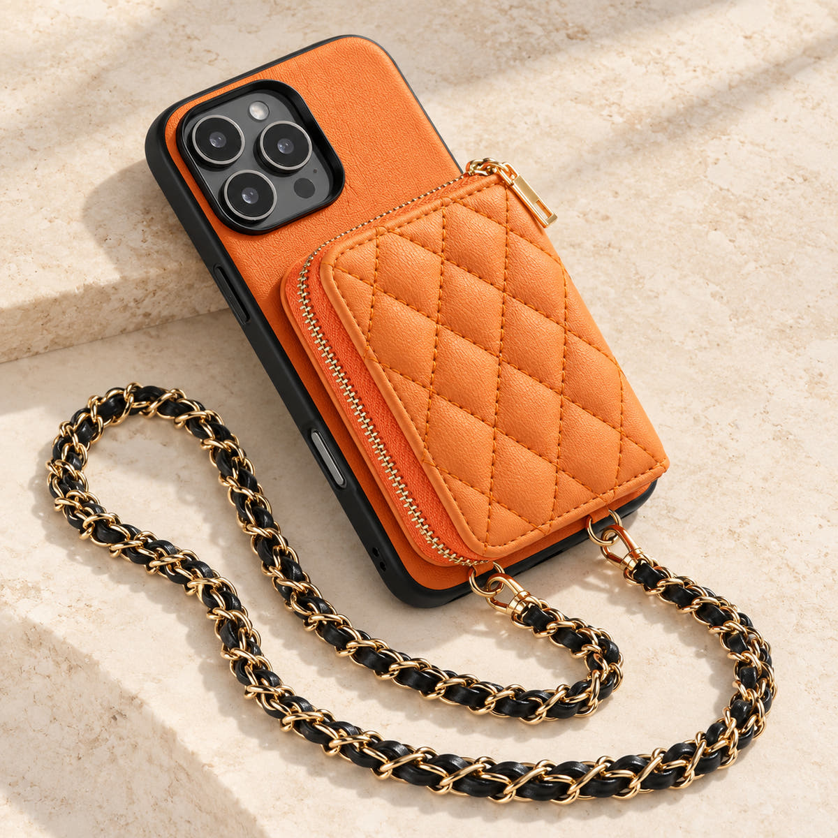 Orange quilted iPhone wallet case — quilted wallet and woven chain on a tabletop