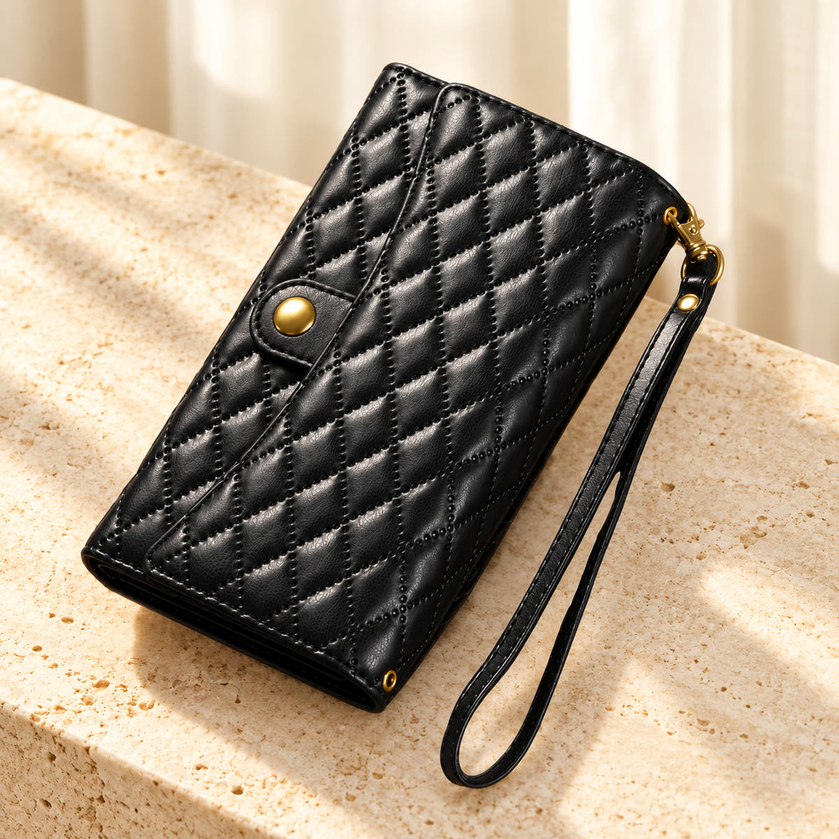 Quilted Zip Wallet iPhone case in Black on cream limestone, with the closed diamond-quilted front, snap flap and matching wrist loop.