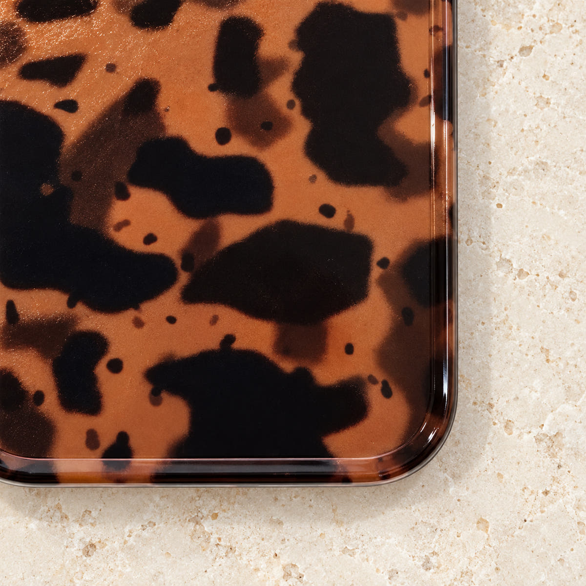 Close-up of the lower rear corner of Sienna Luxe Brown, showing tortoiseshell artwork beneath a smooth glossy surface.