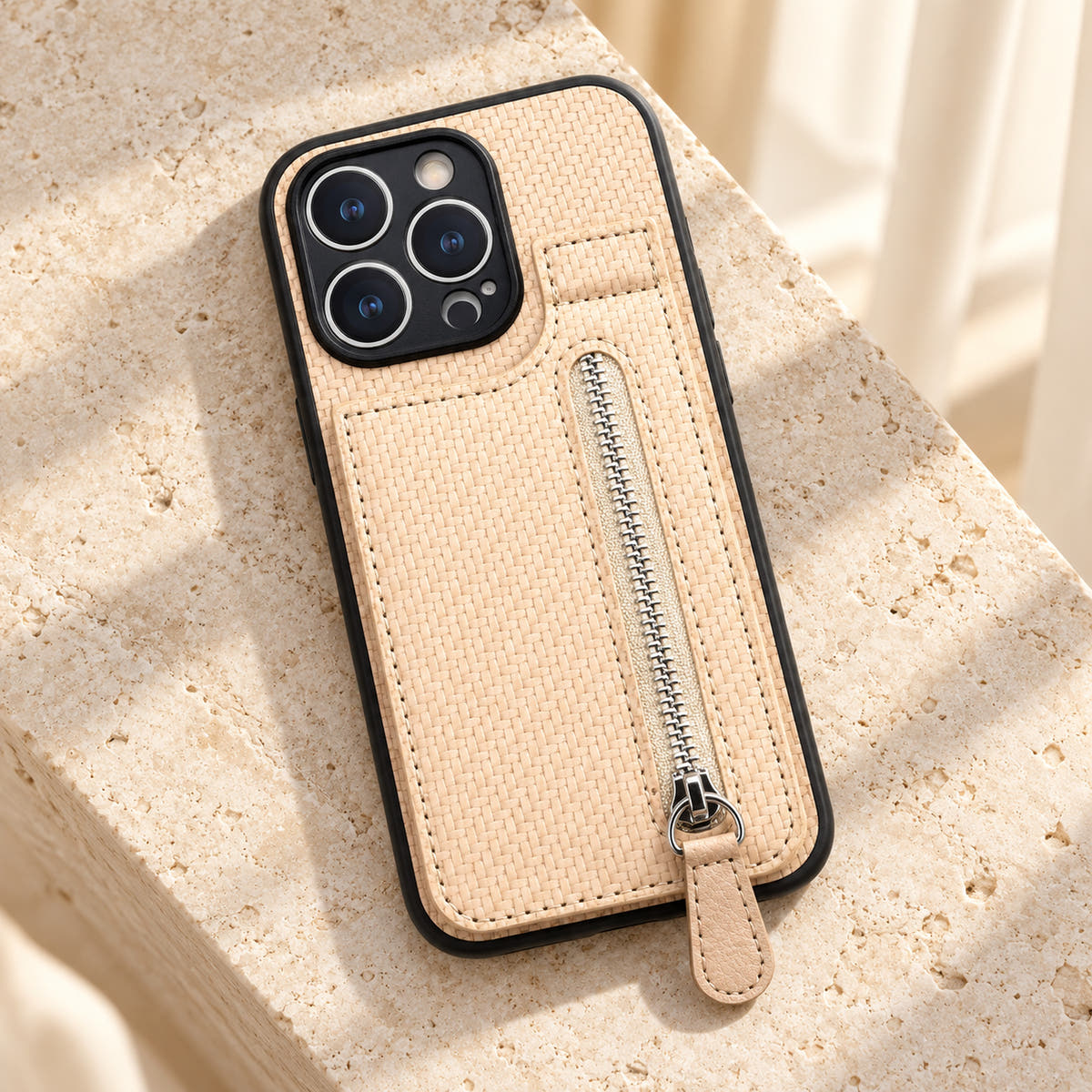 Signature Beige iPhone wallet case resting on cream limestone with its complete textured back and silver-tone zipper visible.