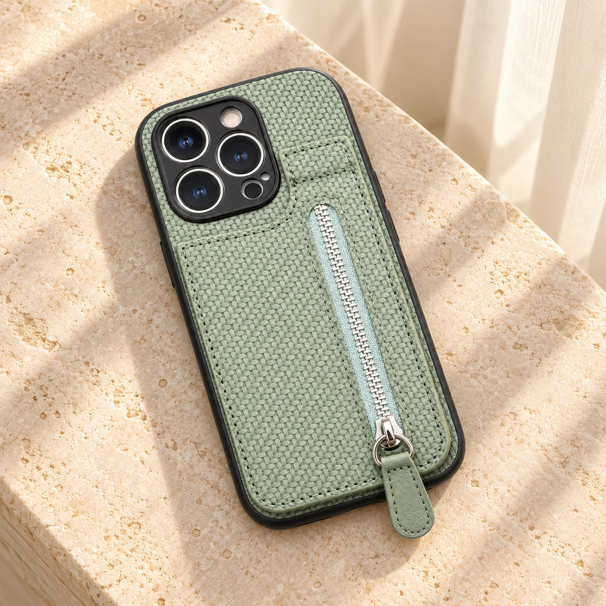Signature Green iPhone wallet case resting on cream limestone with its complete textured back and silver-tone zipper visible.
