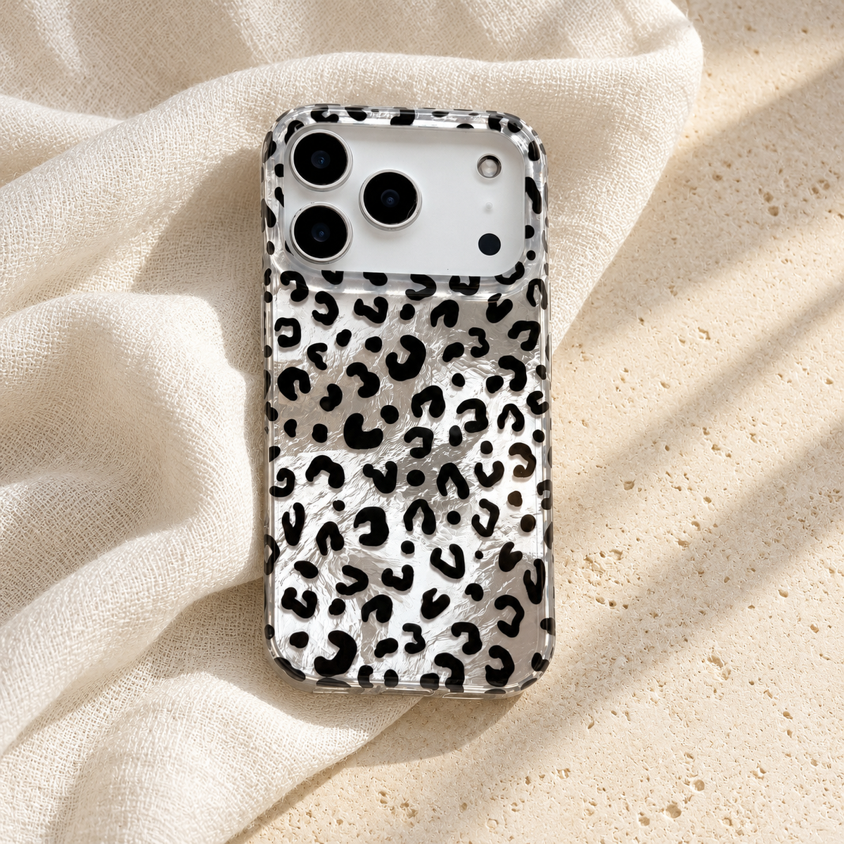 Black leopard iPhone case on ivory linen under soft natural light.