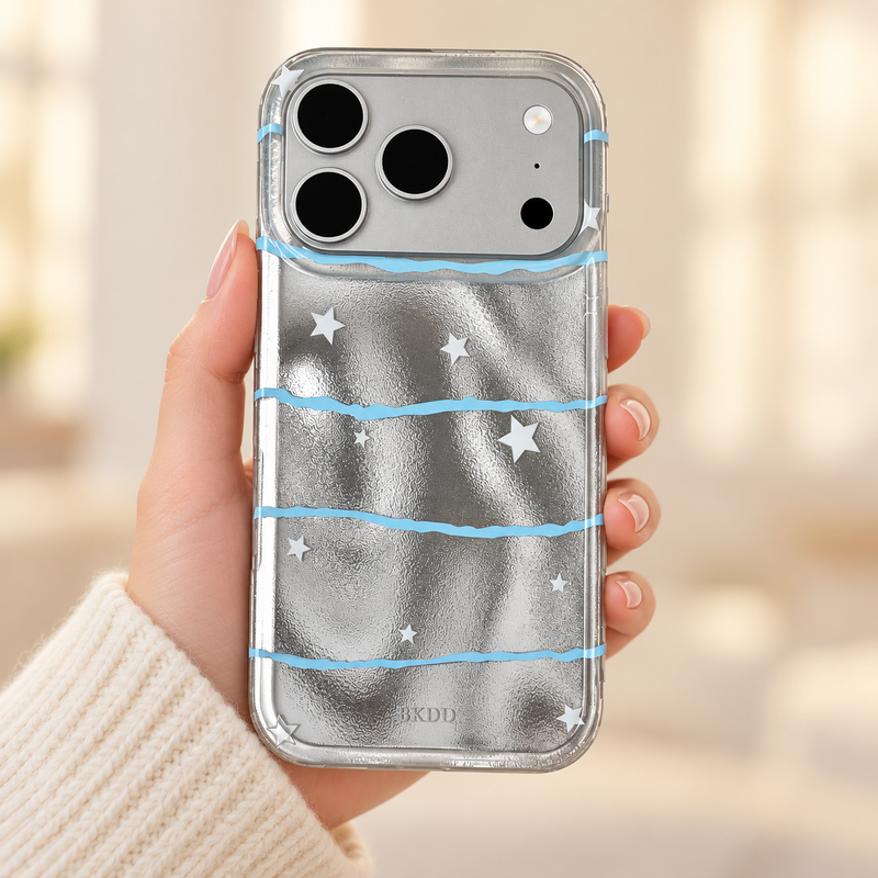 Silver Star Wave iPhone case held upright in one hand, showing the reflective silver back, pale-blue waves and white stars.