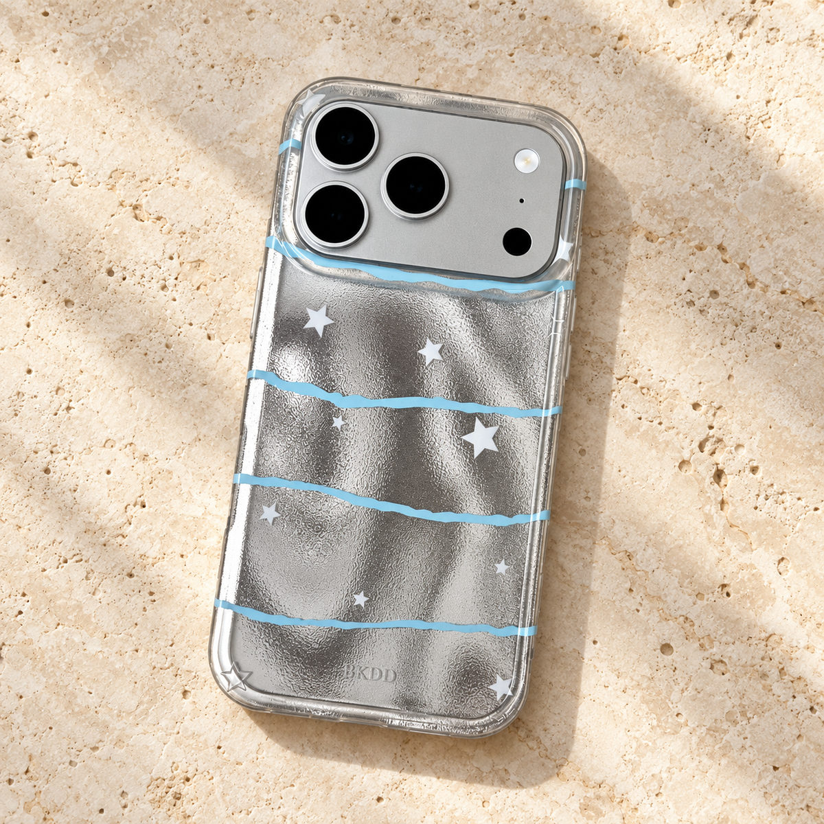 Overhead view of the Silver Star Wave case on warm cream stone, showing the full blue-wave and white-star design.