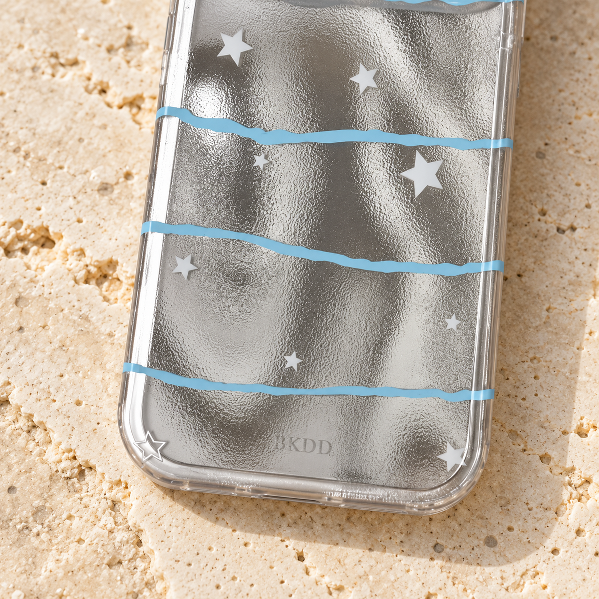 Lower detail of the Silver Star Wave case showing the rounded clear edge, white stars, blue wave and small printed mark.