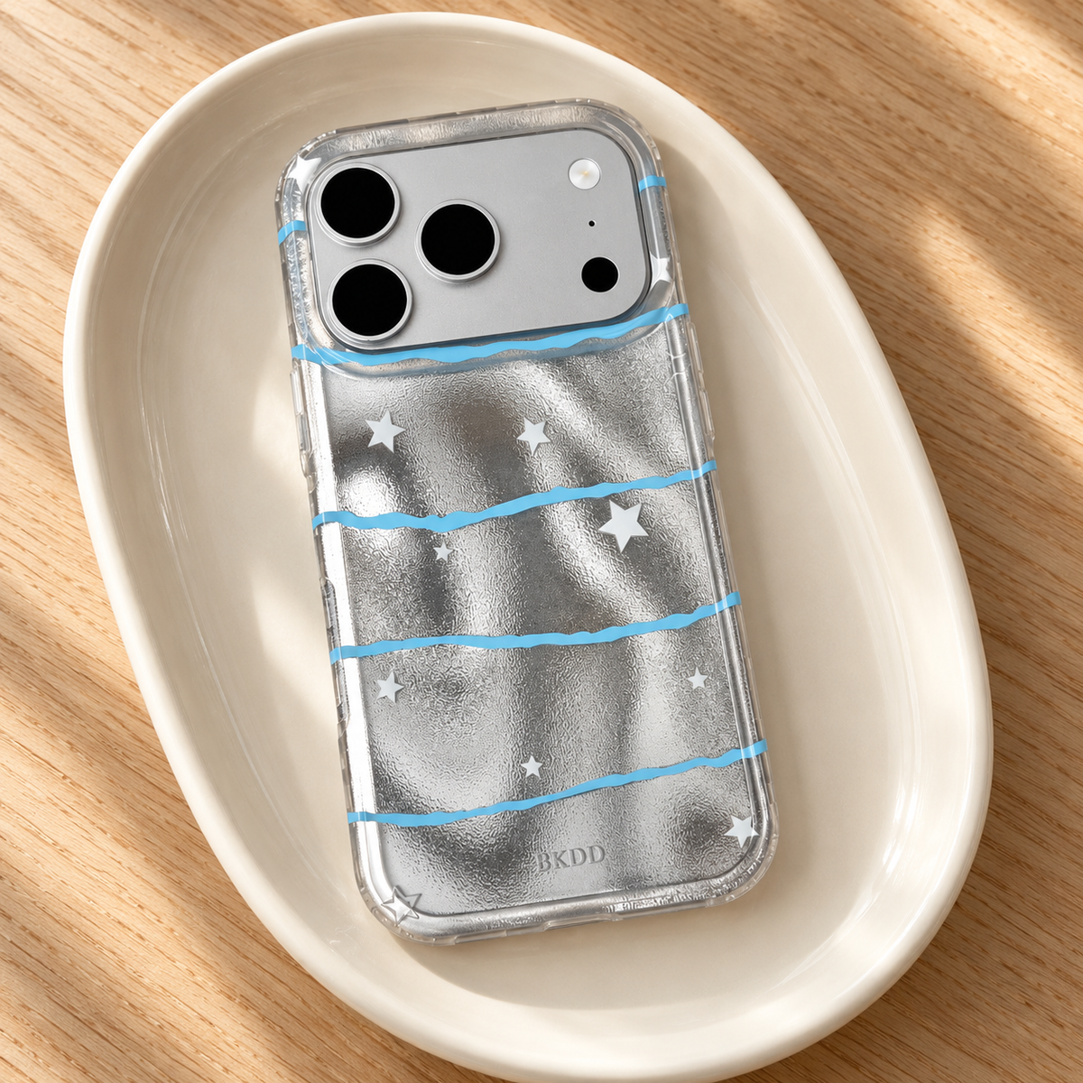 Silver Star Wave case styled in a simple ivory tray on a light oak tabletop.