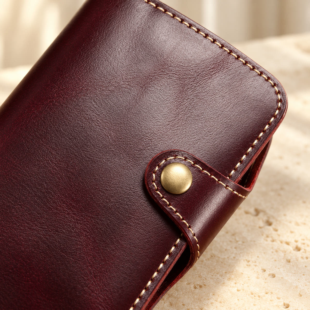 Close-up of the red wallet case button tab, contrast stitching and textured front