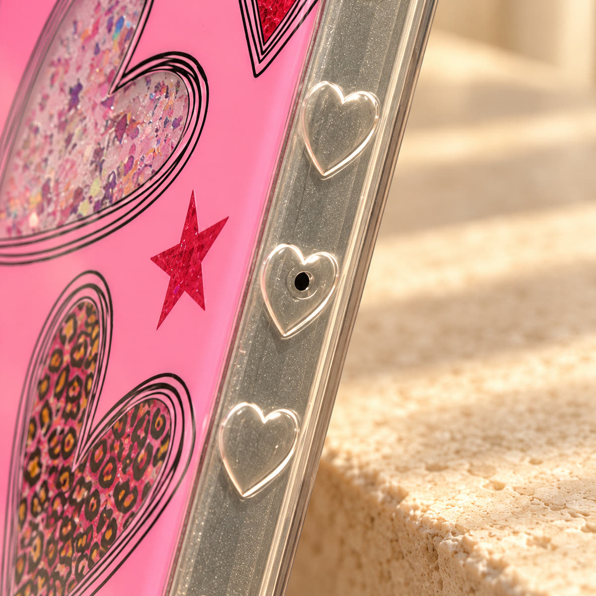 Close-up of the moulded heart accents on the clear side rim of the Valentina Sparkle Heart Pink iPhone case.