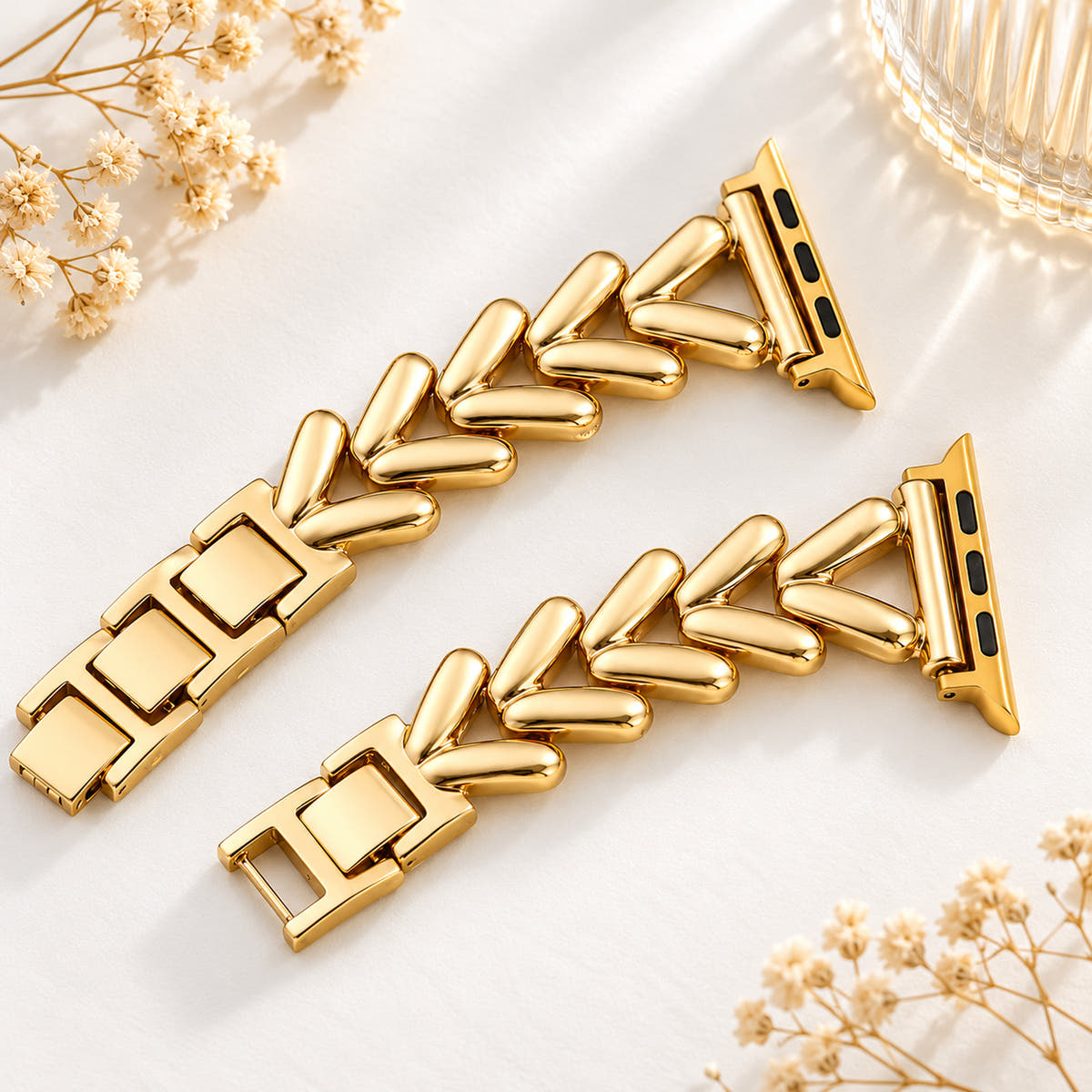Two halves of the Monelle gold-tone chevron Apple Watch band with adapters and clasp links