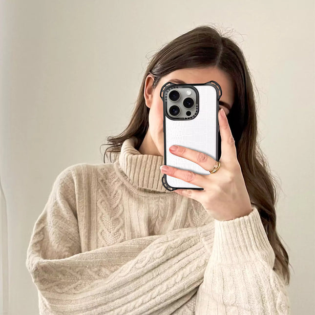Woman in beige sweater holding an iPhone 15 Pro Max with a White Smoke Alligator Bounce Case