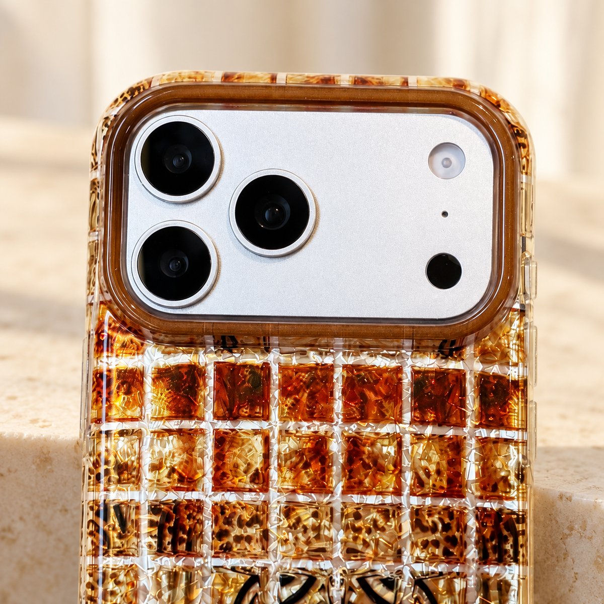 Camera surround and upper-edge detail of the Plaid Amber Shimmer iPhone case.