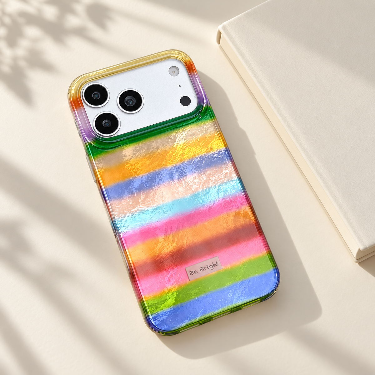Be Bright rainbow stripe iPhone case — everyday desk styling.
