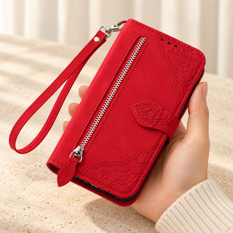 Botanical embossed iPhone wallet case in Red, handheld front view with silver zip pocket, leaf-shaped pull and matching wrist loop.