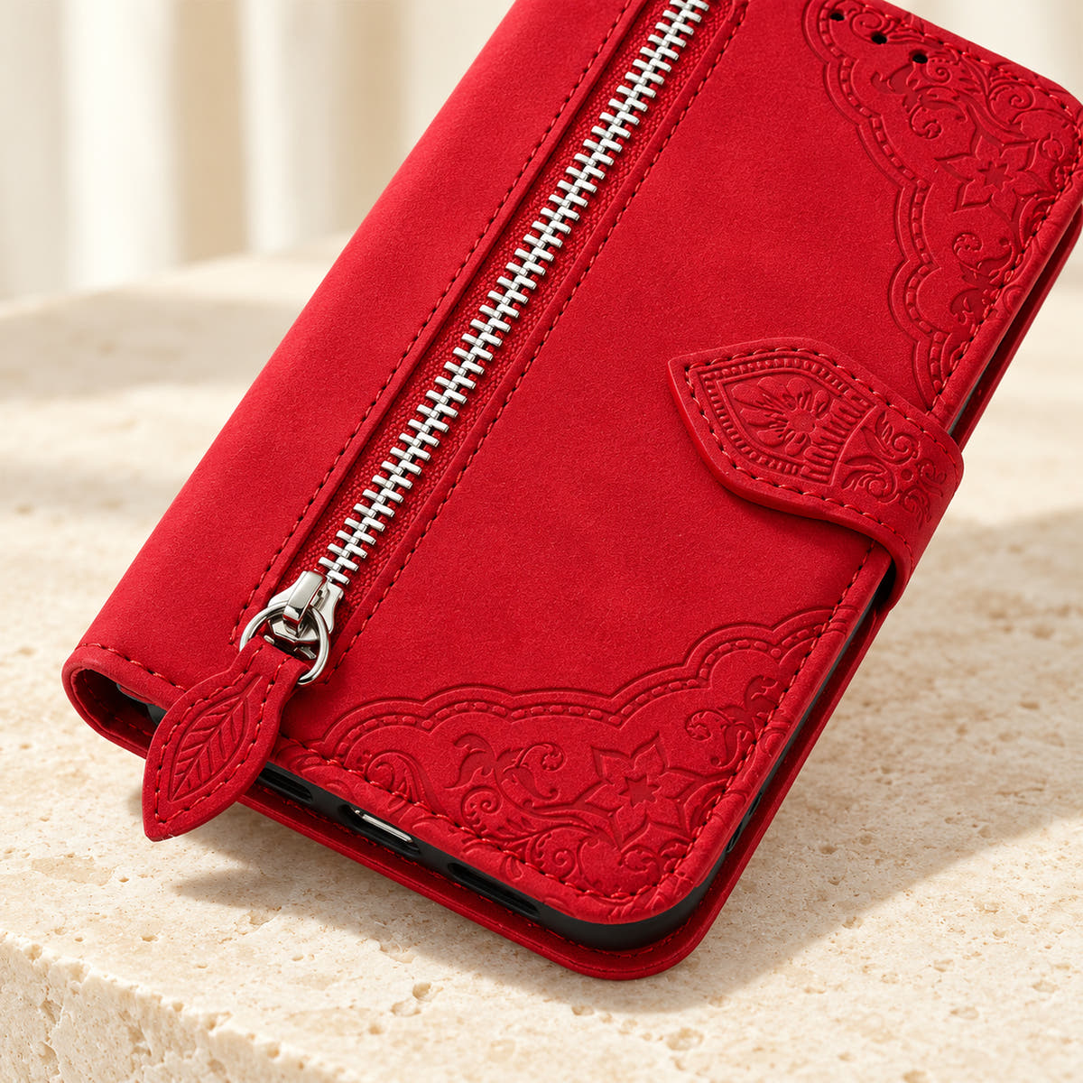 Close-up of the Red Botanical wallet case showing the silver zipper, leaf-shaped pull, embossed floral border and stitching.