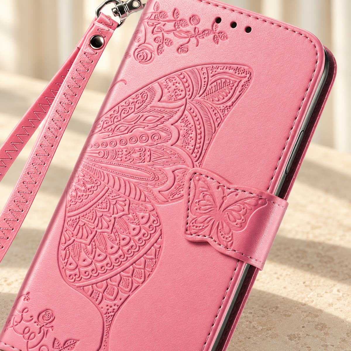 Close-up of the Pink Butterfly wallet phone case showing the intricate embossed wing, small butterfly tab and stitched edge.