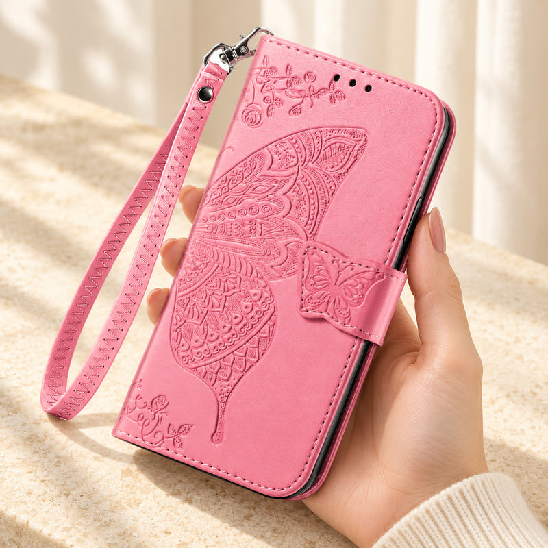 Butterfly embossed iPhone wallet case in Pink, handheld closed-front view with butterfly tab and matching wrist loop.