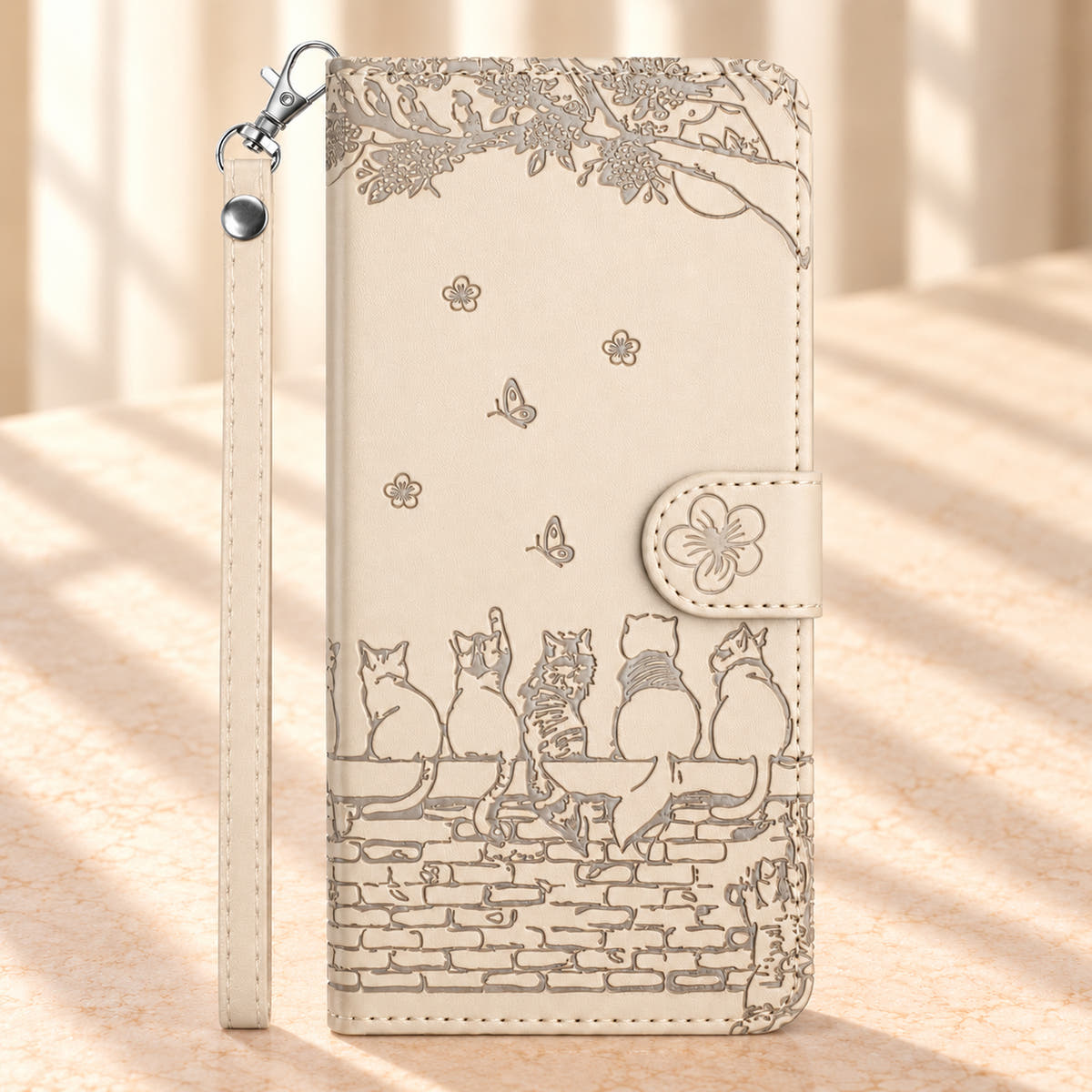 Front of the Ivory Cat Garden wallet case with an embossed cat and brick-wall scene, flower closure and wrist strap.
