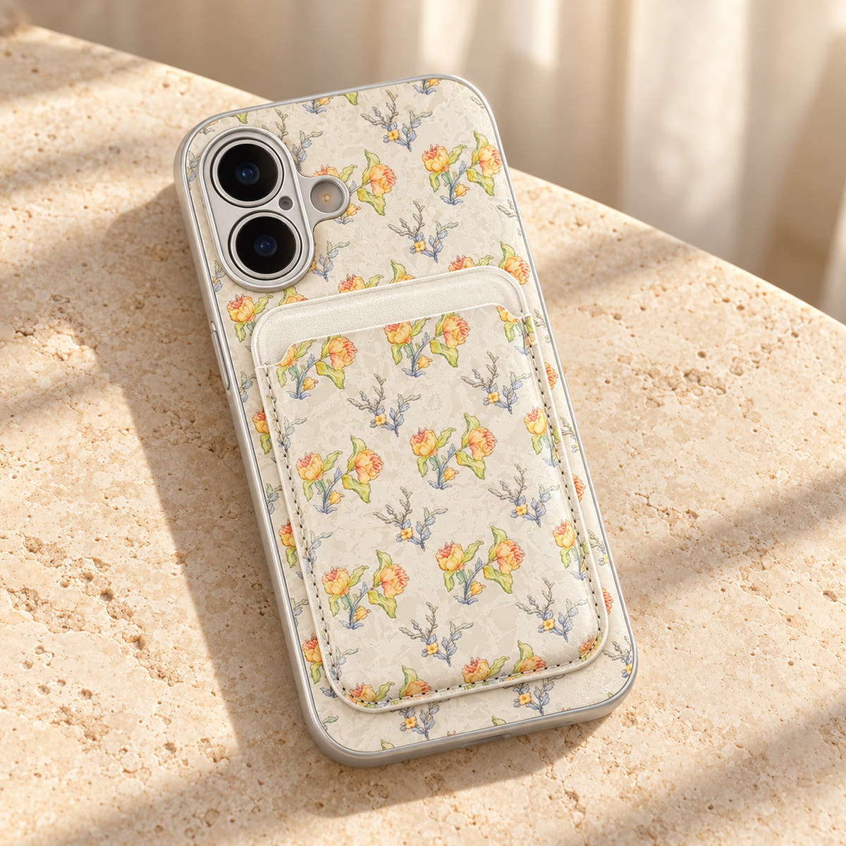 Yellow Elysia Floral phone case and attached card wallet resting on a warm cream stone tabletop.