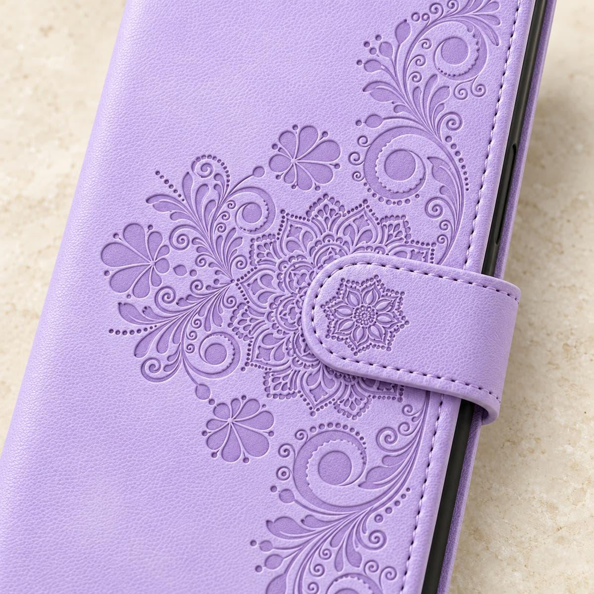 Floral embossed iPhone flip wallet case in Lavender — close-up of floral embossing, closure tab and stitching