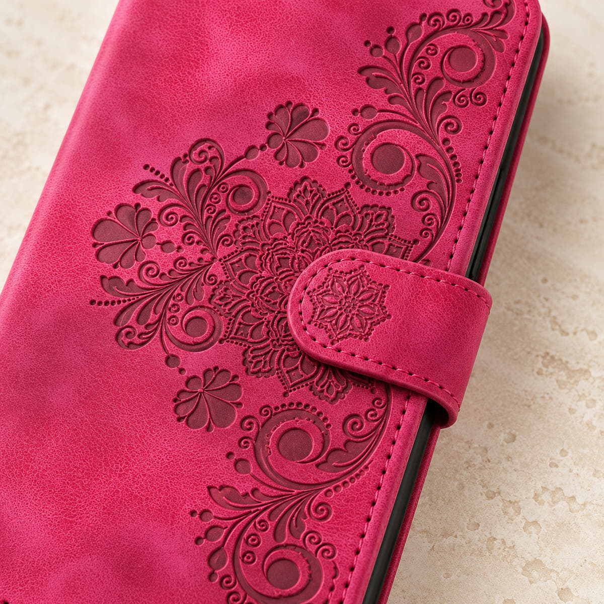 Floral embossed iPhone flip wallet case in Red — close-up of floral embossing, closure tab and stitching