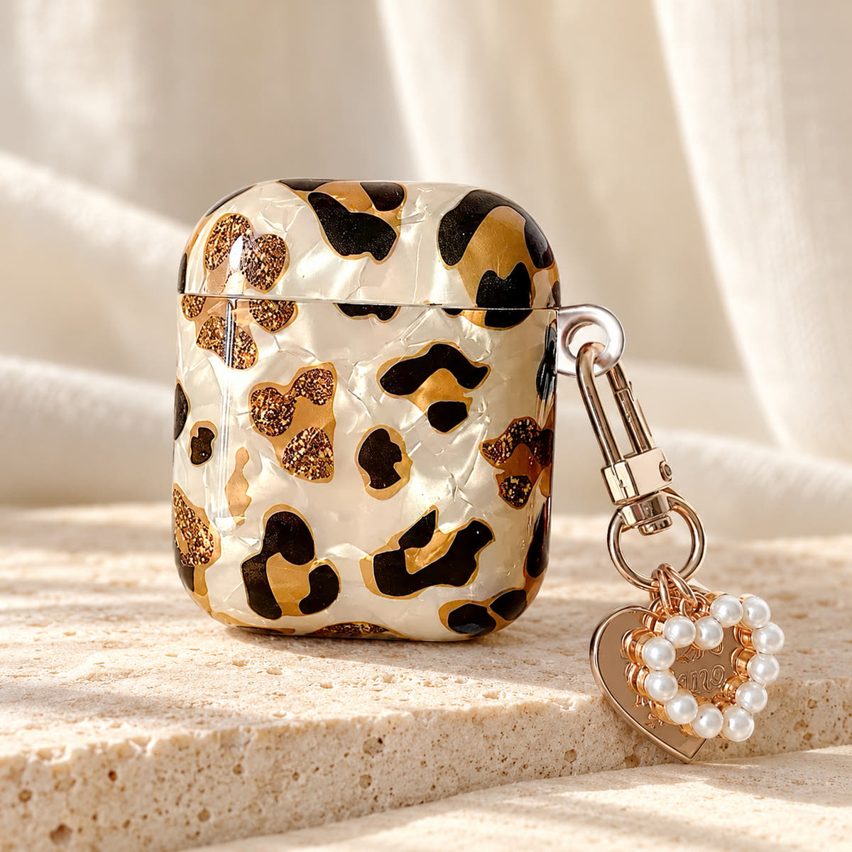 Gilded Leopard Heart AirPods case Design #2 — tabletop showing its pearl-style heart charm
