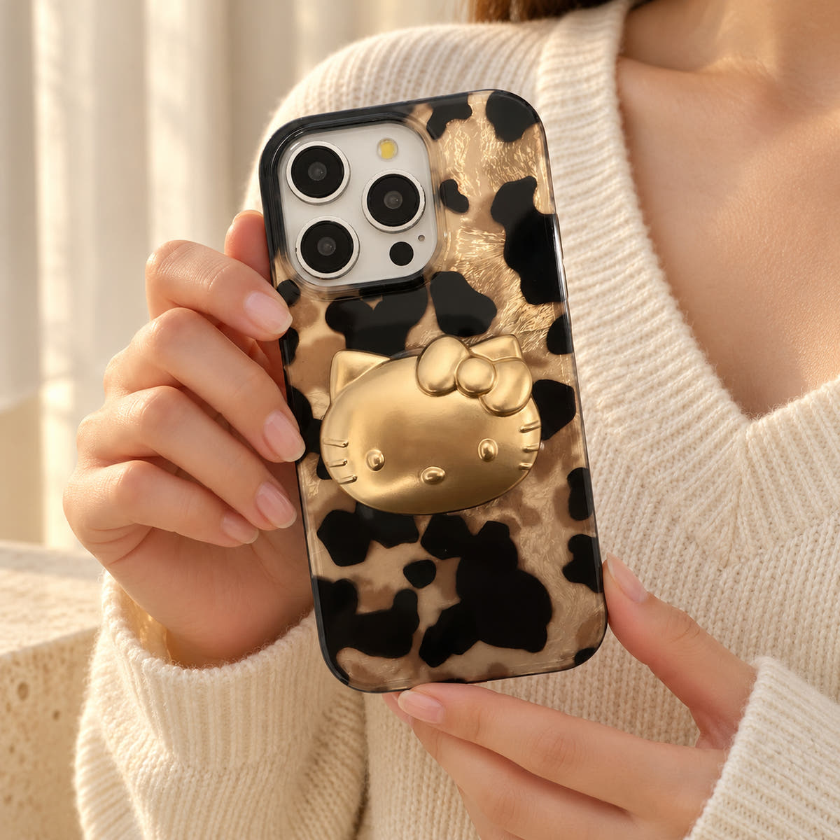 Glam Kitty case with kitty held at chest level against a cream knit outfit in soft daylight.