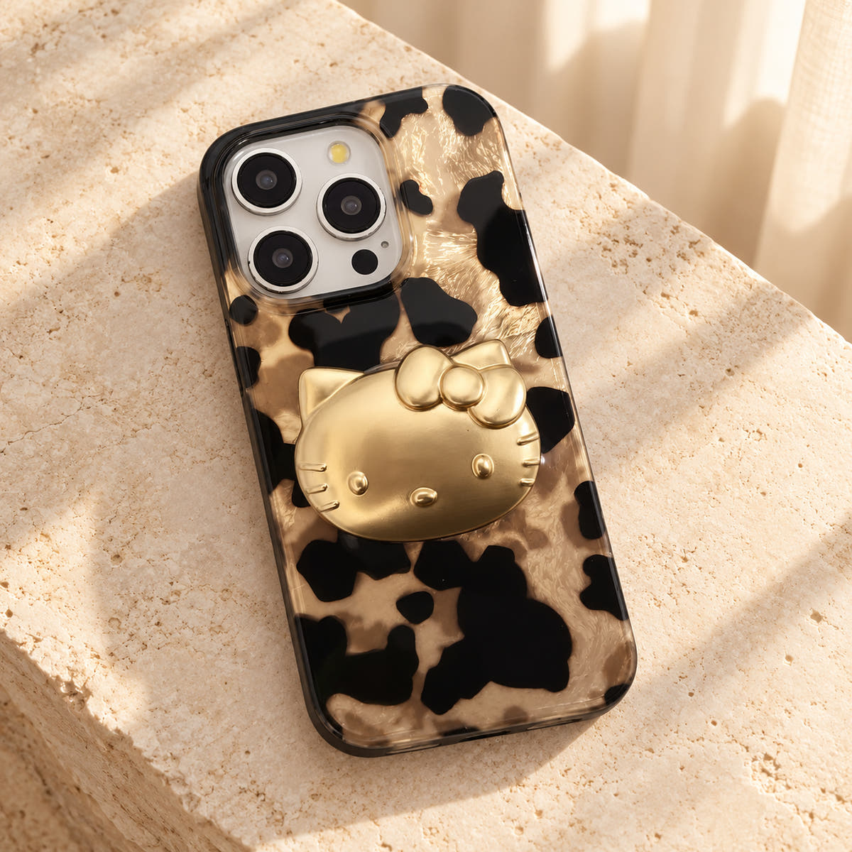 Glam Kitty case with kitty resting diagonally on cream limestone with its glossy rear visible.