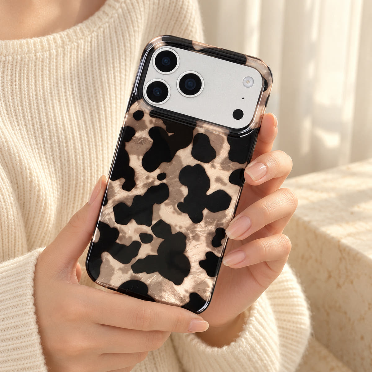 Glam Kitty case without kitty held at chest level against a cream knit outfit in soft daylight.
