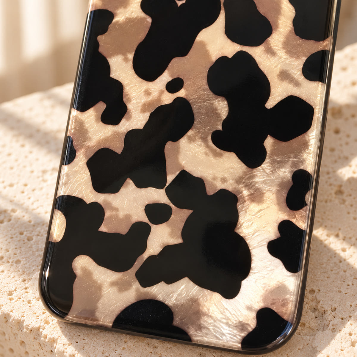 Glam Kitty case without kitty in a detail view of its black leopard pattern and champagne-toned background.