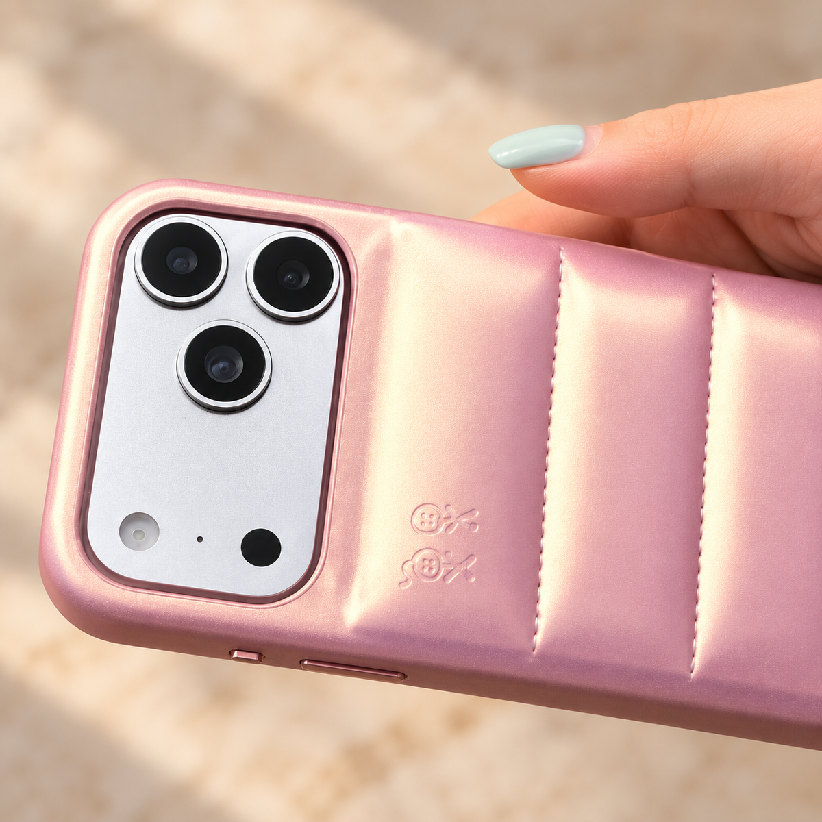 Horizontal handheld detail of the Iridescent Pink puffer case, showing the original camera opening and raised rear sections.