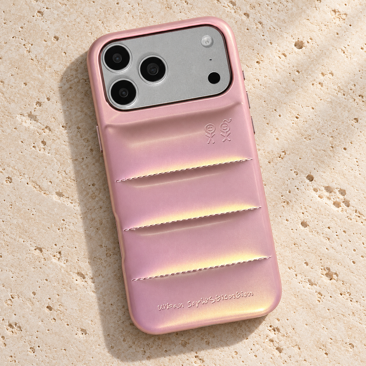 Iridescent Pink puffer phone case lying on textured pale travertine.
