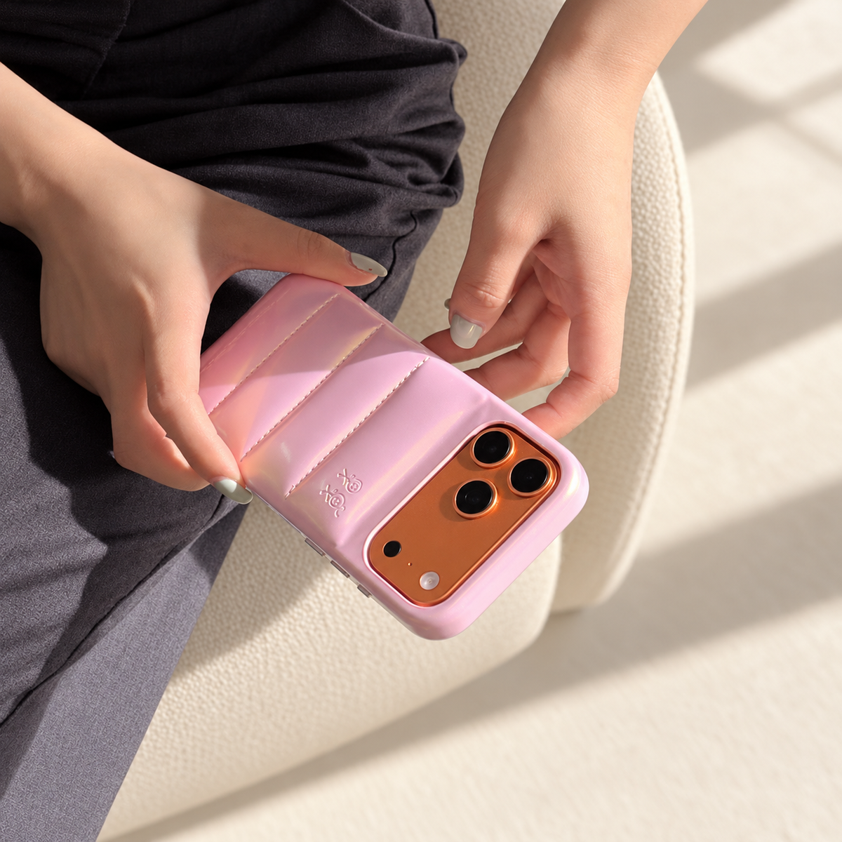 Iridescent Pink puffer case held across the lap with the embossed figures and original camera opening visible.