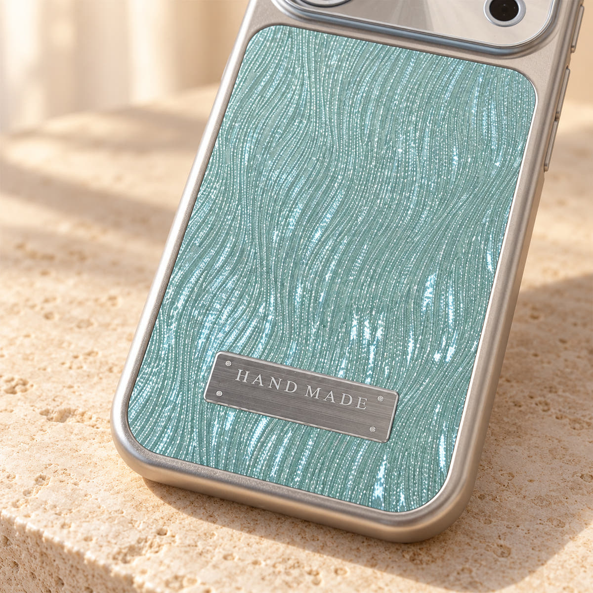 Luna Belle textured shimmer iPhone case in Ice Blue, close-up of the wave texture and silver-tone plaque.