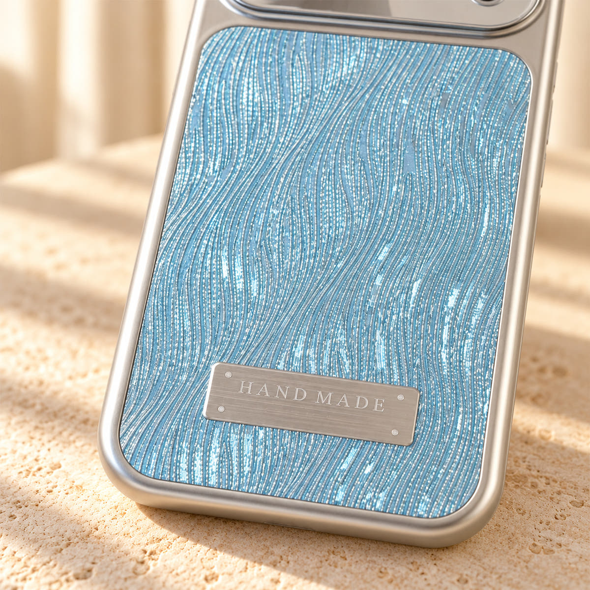 Luna Belle textured shimmer iPhone case in Sky Blue, close-up of the wave texture and silver-tone plaque.