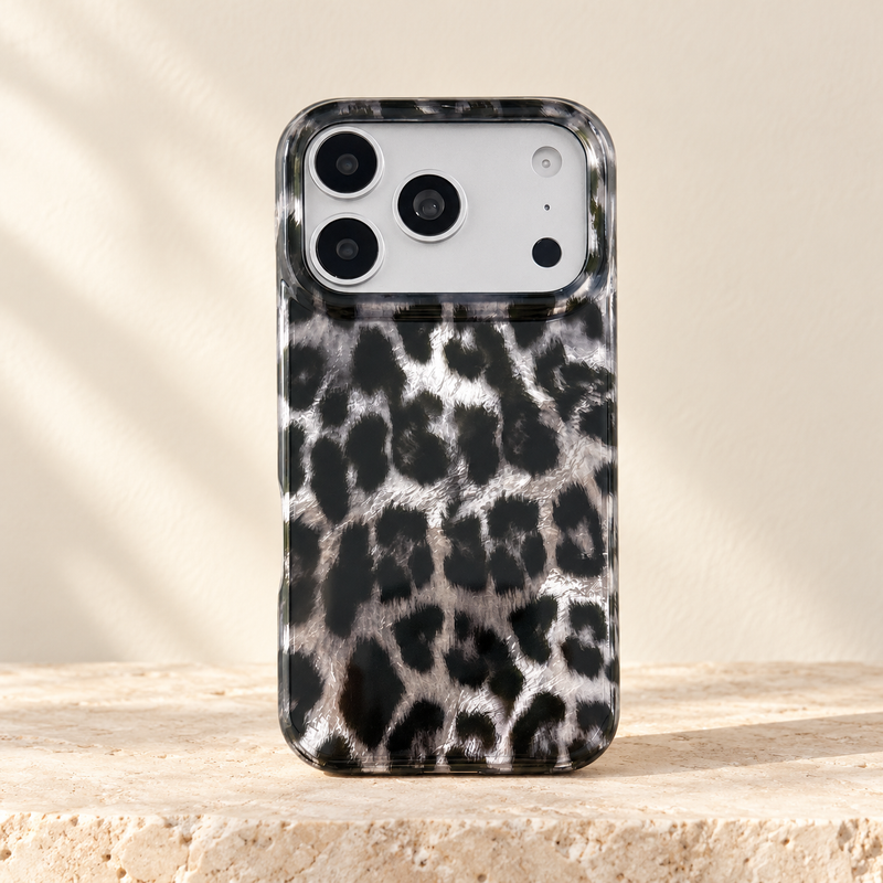 Black and silver leopard print iPhone case with clear edges on pale limestone.
