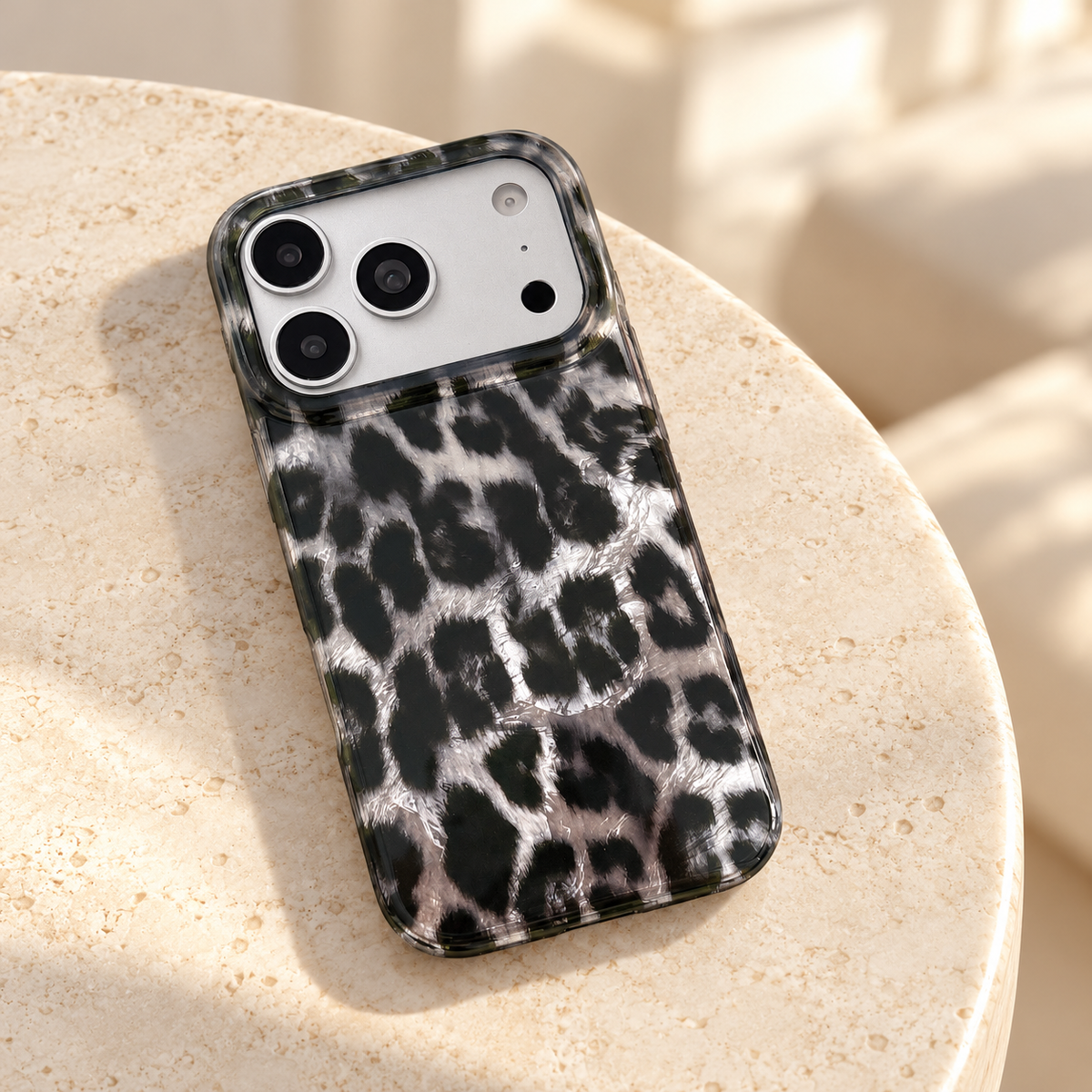 Black and silver leopard print case on a round cream stone side table.