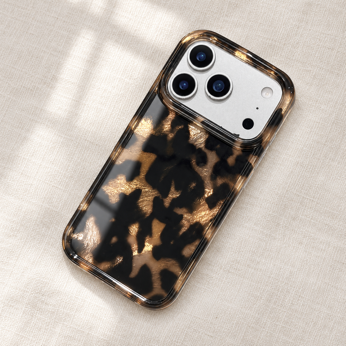 Dark Tortoiseshell iPhone case with black and warm brown mottled pattern — full rear in soft window light.