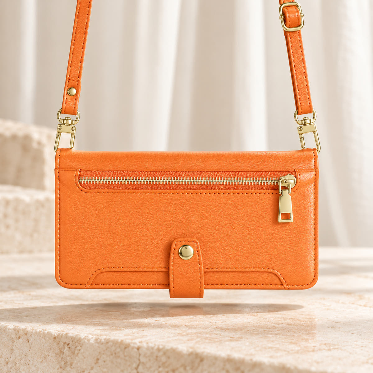 Minimal crossbody iPhone wallet case in Orange — landscape view with long matching shoulder strap and gold-tone clips