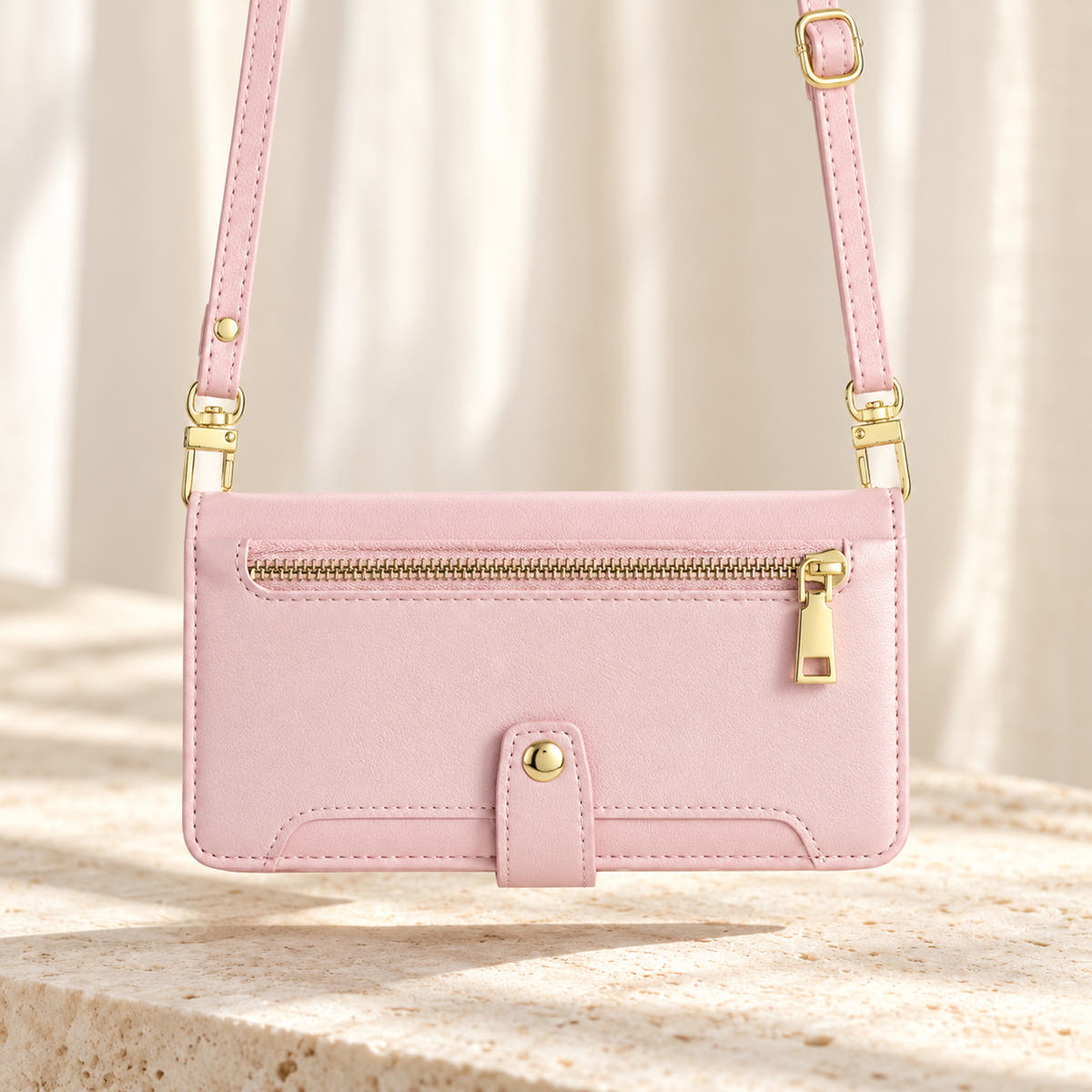 Minimal crossbody iPhone wallet case in Pink — landscape view with long matching shoulder strap and gold-tone clips